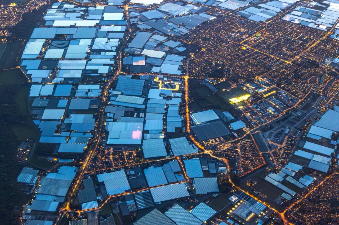 Night aerial view of the Dutch glasshouse belt glowing under a dark sky